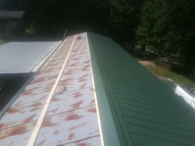 Old rusted panels beside newly installed green metal roofing — Wind Damage Roof Repair by Roofing Brothers in New Brighton