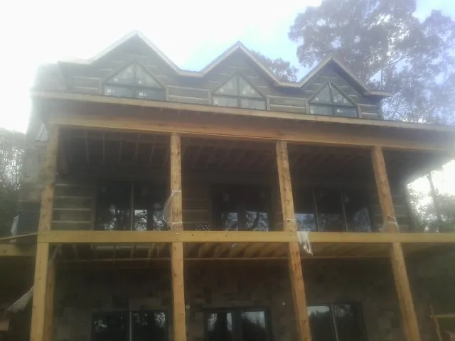 Dormers and porch framing on a large log home under construction — Roof Coating work by our crew in New Brighton