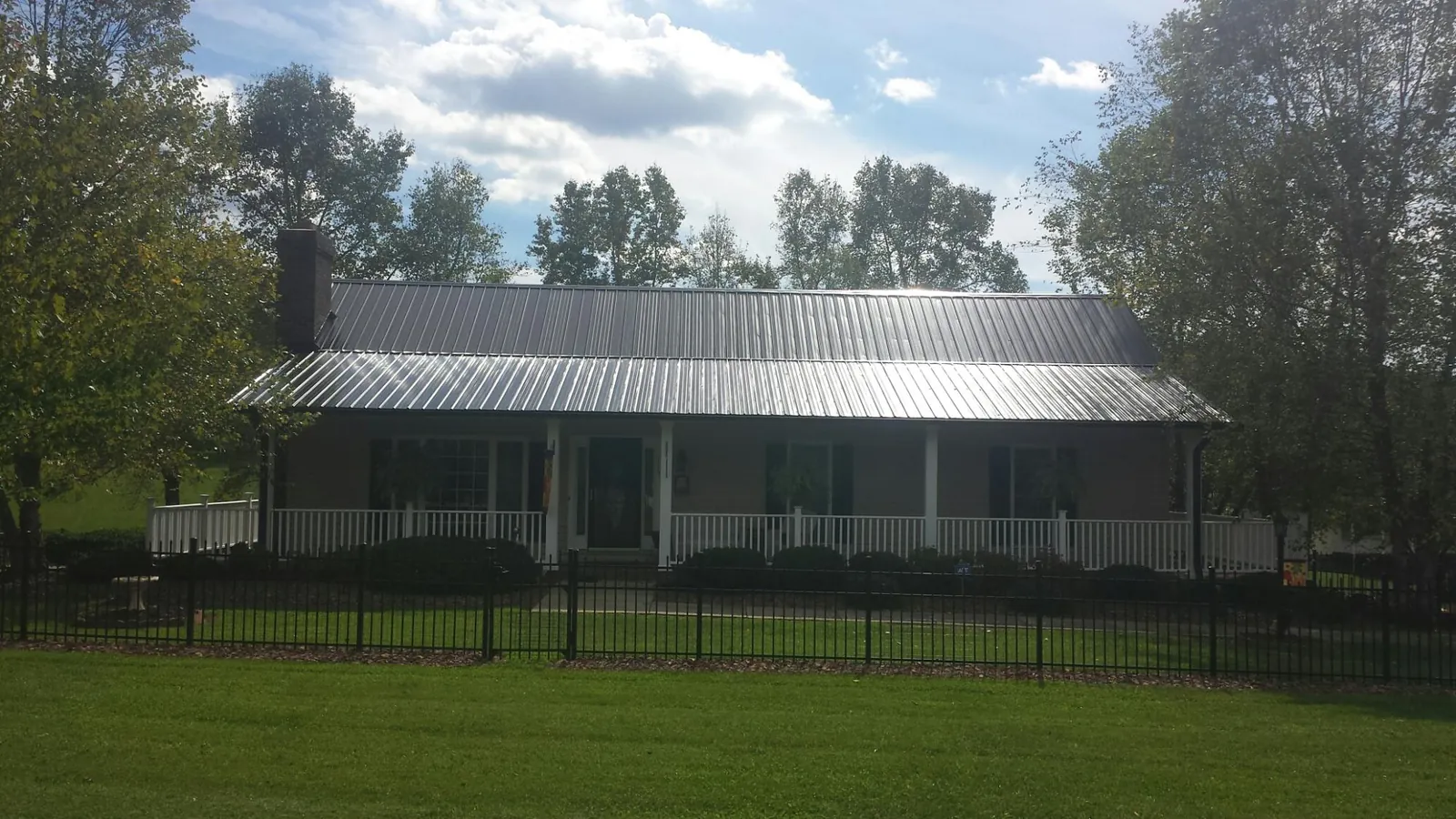 Gray metal roof on a brick ranch with a full width front porch — Gutter Guard Installation work by our crew in New Brighton