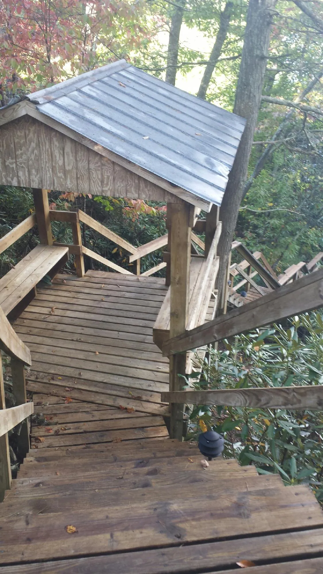 Metal roofed shelter over wooden steps on a wooded walkway — Skylight Repair & Installation work by our crew in New Brighton