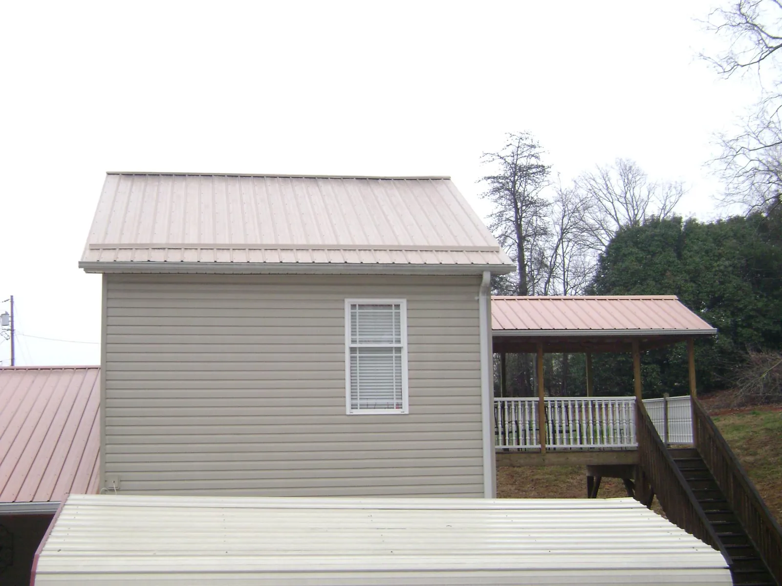 Tan metal roofs on a two story addition and attached porch, from a Roof Replacement job in New Brighton
