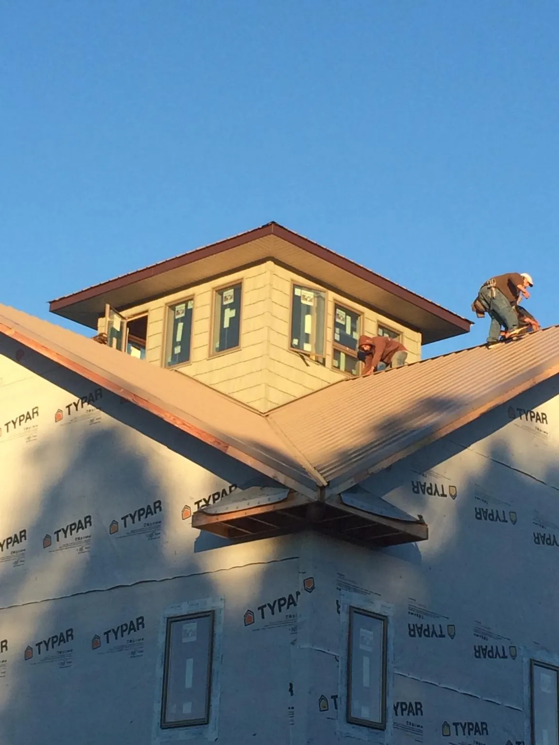 Roofers working around a rooftop cupola on a new metal roof at sunset — Roof Waterproofing in New Brighton by Roofing Brothers